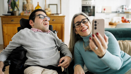 Man with a physical disability sitting in a wheelchair next to a woman smiling and taking a selfie...