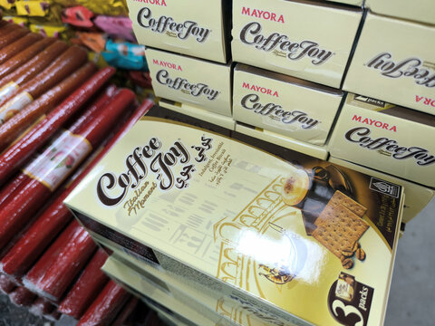 Stack of coffee biscuit boxes arranged on a retail store shelf. Packaged snack product for sale in a grocery market. Commercial food display featuring crackers with coffee flavor.