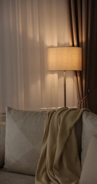 Stylish floor lamp and sofa indoors. Camera moving right