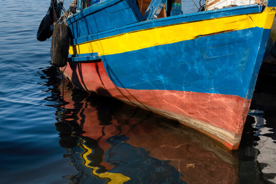 Blue and red fishing boat with yellow details with a crab on the botton right