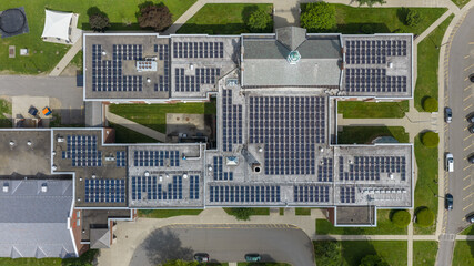 Photo solar panels install on an older, historic, building on a flat commercial, industrial, school roof, with concrete ballast blocks. © Thomas