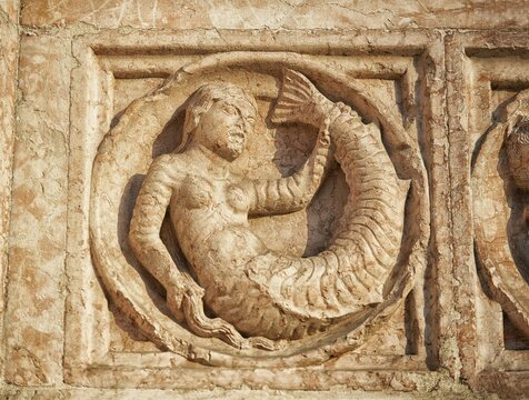 Medieval relief sculpture of mythical mermaid on the exterior of the Romanesque Baptistery, Parma, Emilia Romagna, Italy