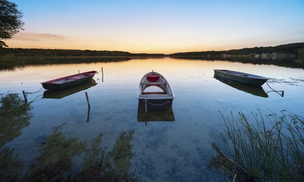 Rowing boats moored in the calm waters of a lake in the evening, Wutzsee, Lindow (Mark), Brandenburg, Germany