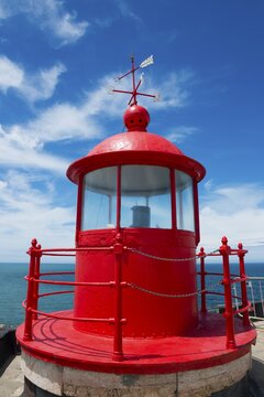 Red lighthouse with round roof on a coastal platform, blue sky and sea in the background, Fort S&atilde;o Miguel Acanjo, Farol de Nazar&eacute;, lighthouse of Nazar&eacute;, S&iacute;tio, Sitio, Nazar&eacute;, Nazare, Oeste, district Leiria, Centro, Estremadura, Portugal