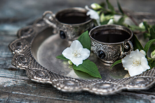Black coffee in vintage silver cups on wooden background