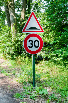 30 km/h speed limit and speed bump road signs on a green country road