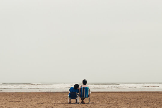 Couple Sitting in Beach Chairs Facing the Ocean, Bertioga, Brazil