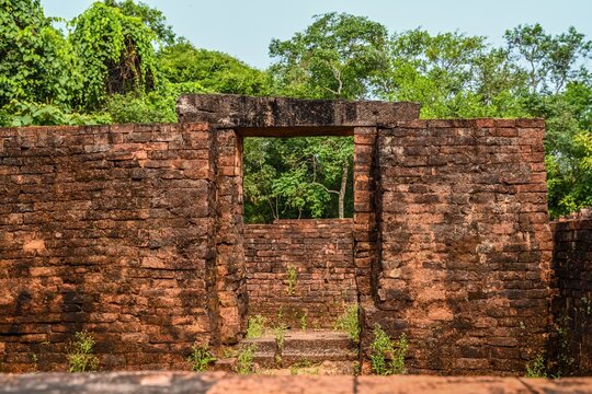 Ancient ruined red brick gate with stone lintel at Hindu temple ruins of My Son Sanctuary in tropical jungle of Vietnam
