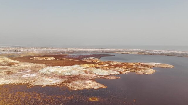 Aerial view of the surreal red and orange acidic salt pools and mineral deposits in the Dallol geothermal area, Danakil Depression, Ethiopia. This unique, harsh landscape looks like another planet.