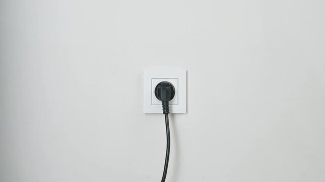 Male Hand Plugging Charger Into White Wall Power Socket