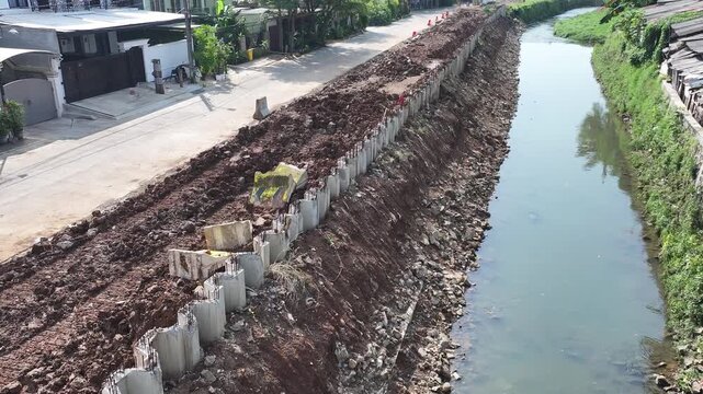 dredging mud on the riverbank in densely populated areas in the city center using heavy equipment such as excavators and dump trucks