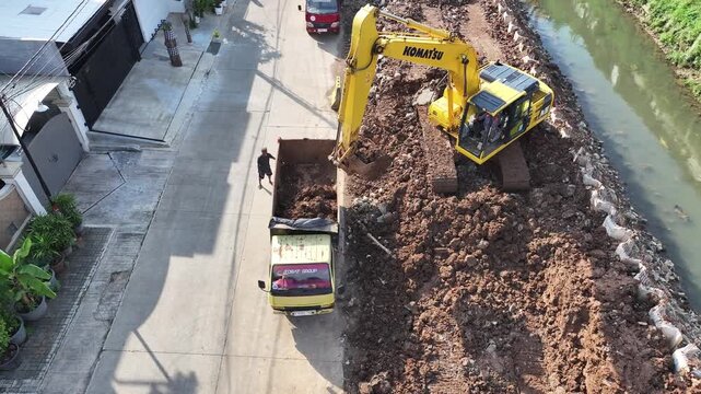 dredging mud on the riverbank in densely populated areas in the city center using heavy equipment such as excavators and dump trucks