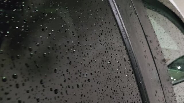 Rain droplets on car window at night with reflections and urban lights