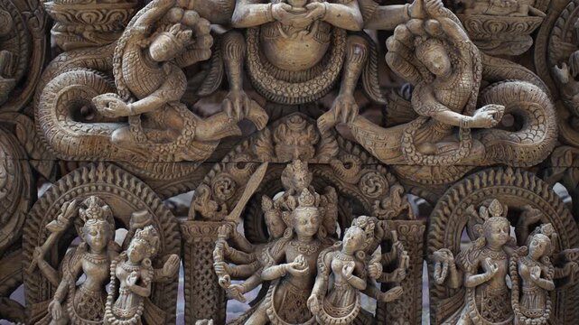 View of intricate traditional wood carvings of Hindu deities with multiple arms and ornate details in a historic temple, Nepal.