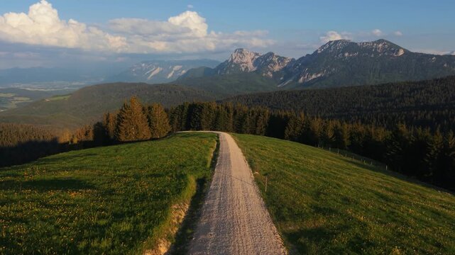 Aerial shot following a alps mountain path at Teisenberg summit during a beautiful spring sunset, Germany.