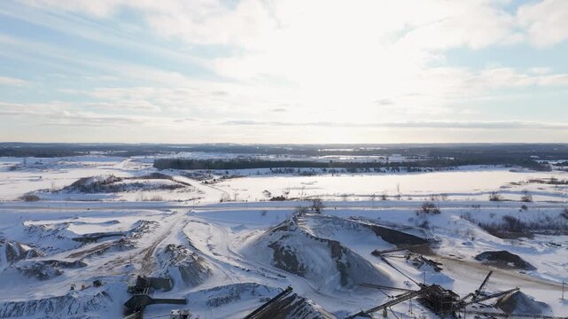Snow-dusted gravel pits stretch across a vast landscape under a sunlit sky. Ideal for environmental documentaries or industrial-themed projects.