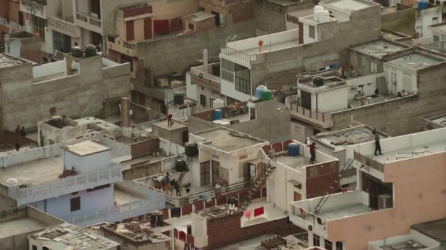Aerial view of a dense urban neighborhood in India where people are flying kites from the rooftops of their homes, a popular pastime and cultural tradition during festivals like Makar Sankranti