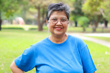 Fototapeta premium Portrait of a smiling senior Asian woman looking at camera with nature background. Exercise for good health in retirement.