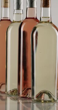 Three elegant bottles of red, white, and r rose wine rotating in slow motion, isolated on a white background, showcasing a modern design perfect for sophisticated marketing campaigns. Vertical.