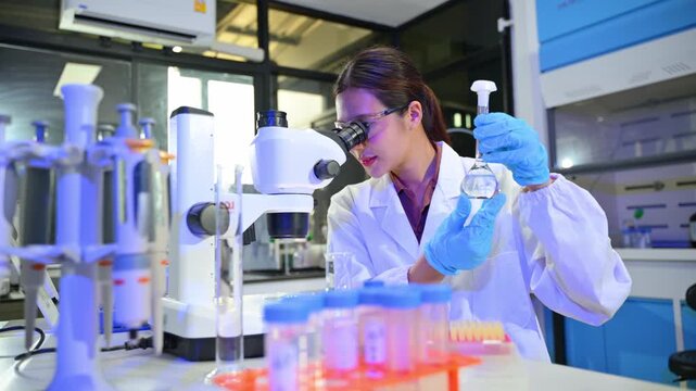 Female Scientist Using Microscope and Laboratory Equipment in Modern Lab