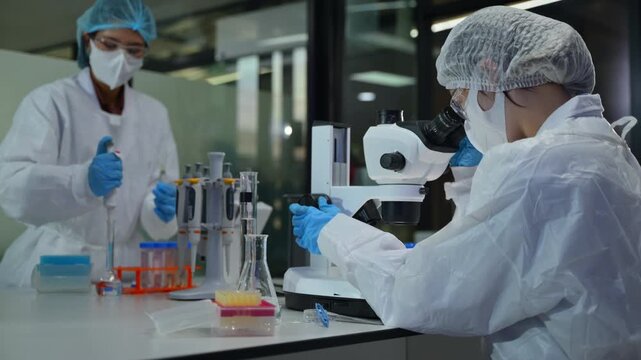 Laboratory scientists conducting research using microscopes and chemical tests in scientific laboratory