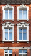 Fototapeta premium A red brick building with white framed windows and ornate details