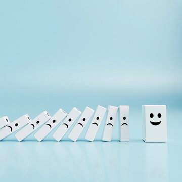 Domino effect with sad faces falling towards a happy face