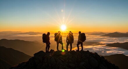 Fototapeta premium Four mountaineers stand silhouetted on a rocky mountain summit at sunrise, celebrating their achievement with a breathtaking vista.
