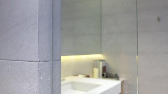 Person Cleaning Soapy Glass Shower Door with a Blue Squeegee