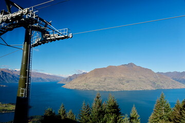 Queenstown, New Zealand - May 20, 2025: A scenic view from the Skyline Gondola over Lake Wakatipu and Cecil Peak. A gondola car is visible, highlighting the popular tourist destination. © Chonlatit