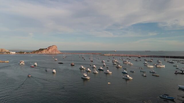 Vista a&eacute;rea del puerto de Mazatl&aacute;n, Sinaloa, M&eacute;xico, mostrando botes, lanchas y yates anclados en aguas tranquilas al atardecer. Escena costera con marina, rompeolas, cielo parcialmente nublado y ambi