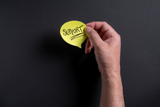 Male hand holding yellow speech bubble with support text on dark background