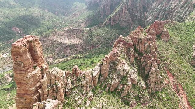 Aerial view of the lush green peaks of Simien Mountains National Park, Ethiopia. A troop of wild gelada baboons rests on a rugged rocky outcrop overlooking the dramatic African highland valley.
