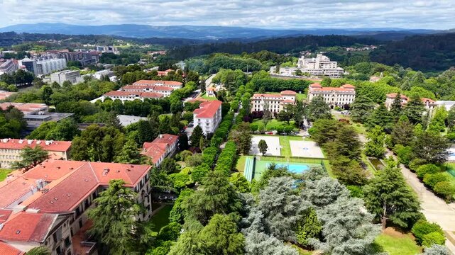 4K Aerial view of the South Campus (Campus Sur) in Santiago de Compostela. Cinematic drone shot showcasing the athletics running track, university student residences, and green parks surrounded by aca