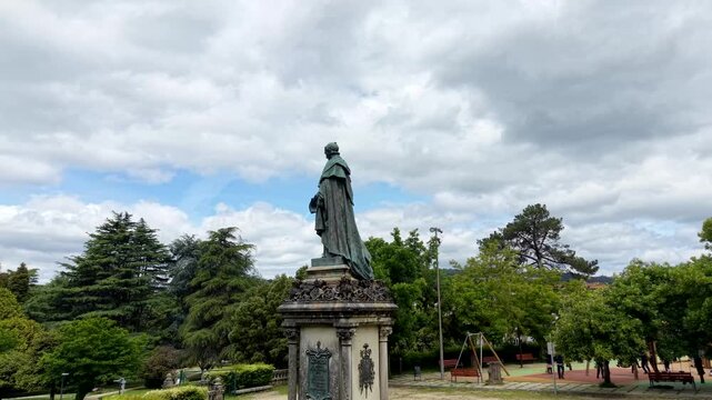 4K Drone orbit shot around the bronze statue of Manuel Ventura Figueroa at the South Campus (Campus Sur) in Santiago de Compostela. Cinematic aerial rotation showing the monument with university build