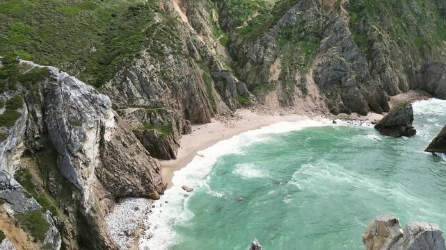Aerial drone footage of Praia da Ursa, Portugal: dramatic sea stacks, Atlantic waves and rugged coastal scenery under natural light. Ideal for travel and nature projects.