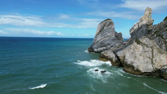 Aerial drone footage of Praia da Ursa, Portugal: dramatic sea stacks, Atlantic waves and rugged coastal scenery under natural light. Ideal for travel and nature projects.