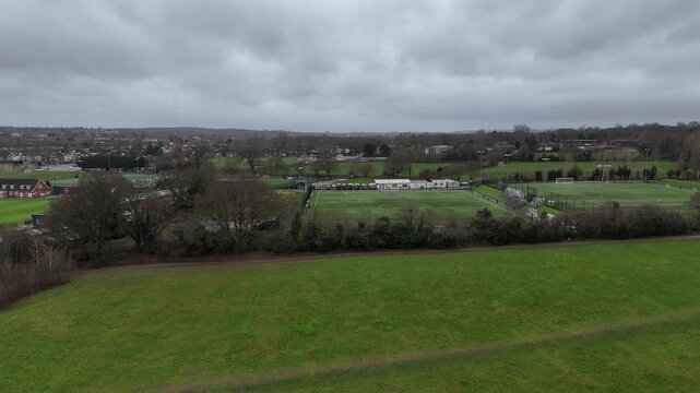 Aerial pull back revealing Avery Hill Park, football pitches, trees and cloudy London skyline.