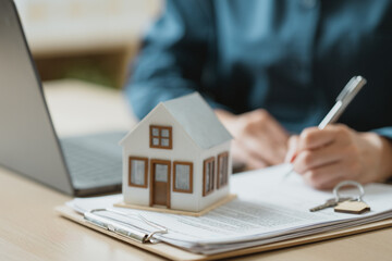 Naklejka premium Real estate mortgage and property purchase concept with house model, contract documents, and key symbolizing home ownership, financing, and legal agreement.
