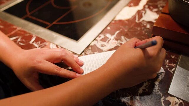 Close Up of Hands Writing Food Order at Asian Buffet Restaurant