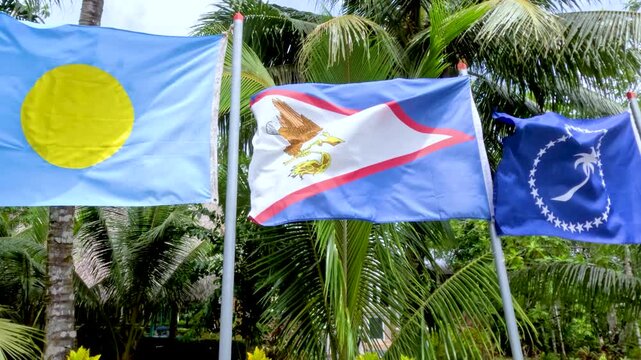National Flags of Palau and American Samoa Waving in Tropical Breeze