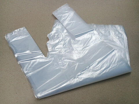 Clear plastic shopping bag with handles on a brown background