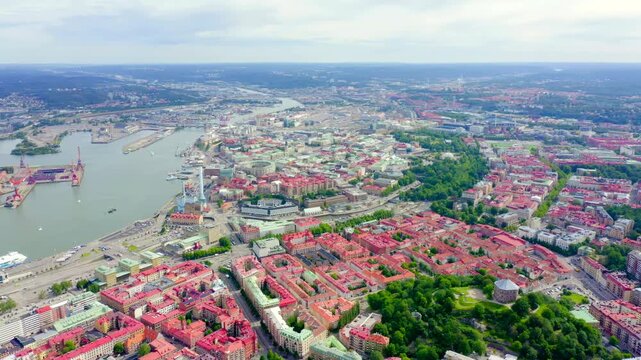 Gothenburg, Sweden. Panoramic Drone footage over the historic city center and the Gota Alv river, dense red rooftops and green parkland under an overcast summer sky. Drone footage