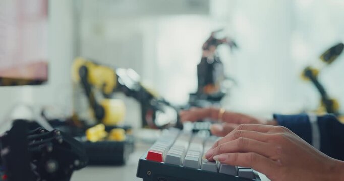 Close-up young Black female robotics engineer coding AI software for robotic arm in laboratory. Embedded system, firmware testing, machine learning, industrial automation, future technology concept.