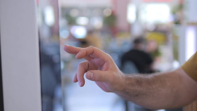 Hand taps touchscreen in modern office. Focus on interaction with digital device. Blurred background shows workspace activity. Ideal for tech, workplace, or digital interface themes