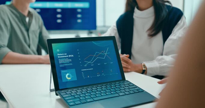 Closeup group Asian businesspeople work together discuss plan idea with investment profit sale statistics in business meeting in office. Financial generation z team brainstorm on e-Commerce project.