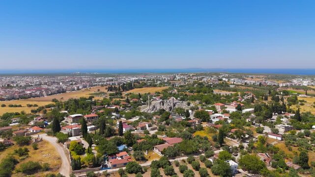 Didim, Turkey. Temple of Apollo at Didyma, soaring Ionic columns and scattered stone ruins amid olive groves and farmland, aerial drone view under clear summer sky with Aegean Sea on the horizon. Aer