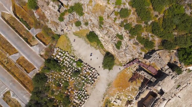Demre, Turkey. Ancient Lycian rock-cut tombs of Myra, temple-front facades carved into sheer limestone cliffs, aerial drone view over the necropolis and Roman theatre. Aerial View, HEAD OVER SHOT wit