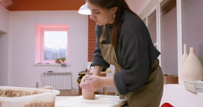 Manufacturing earthenware. Shaping clay. Experienced woman artisan molding raw for ceramic art in professional handmade workspace.