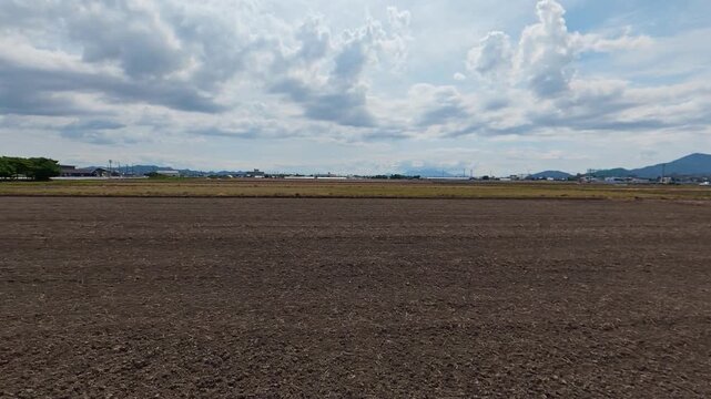 Side tracking shot of an empty unplanted rice field in spring